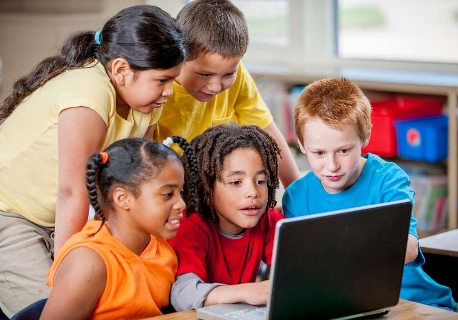 Crianças realizando atividades gamificadas no computador 