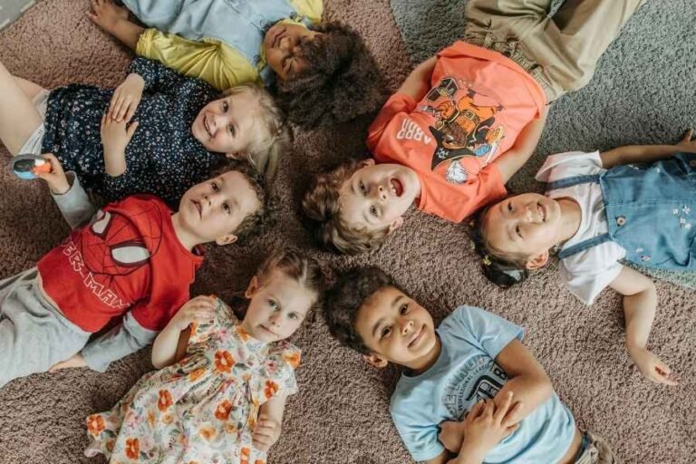 Crinças de 3 a 5 anos deitadas em circulo e sorrindo .